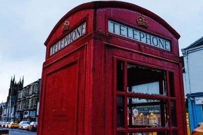 Low angle view of telephone booth against sky in city