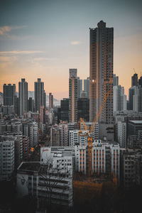 Modern buildings in city against sky during sunset