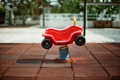 Red toy car on footpath in city