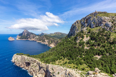 Scenic view of sea by mountain against sky