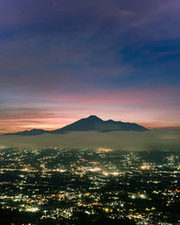Aerial view of illuminated cityscape against sky during sunset