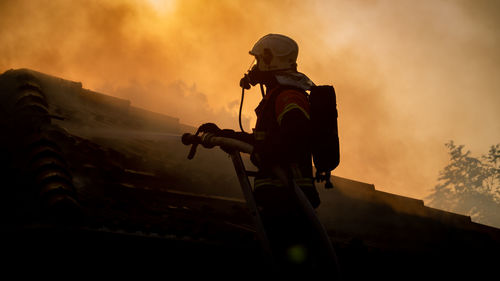 Silhouette firefighter watering built structure