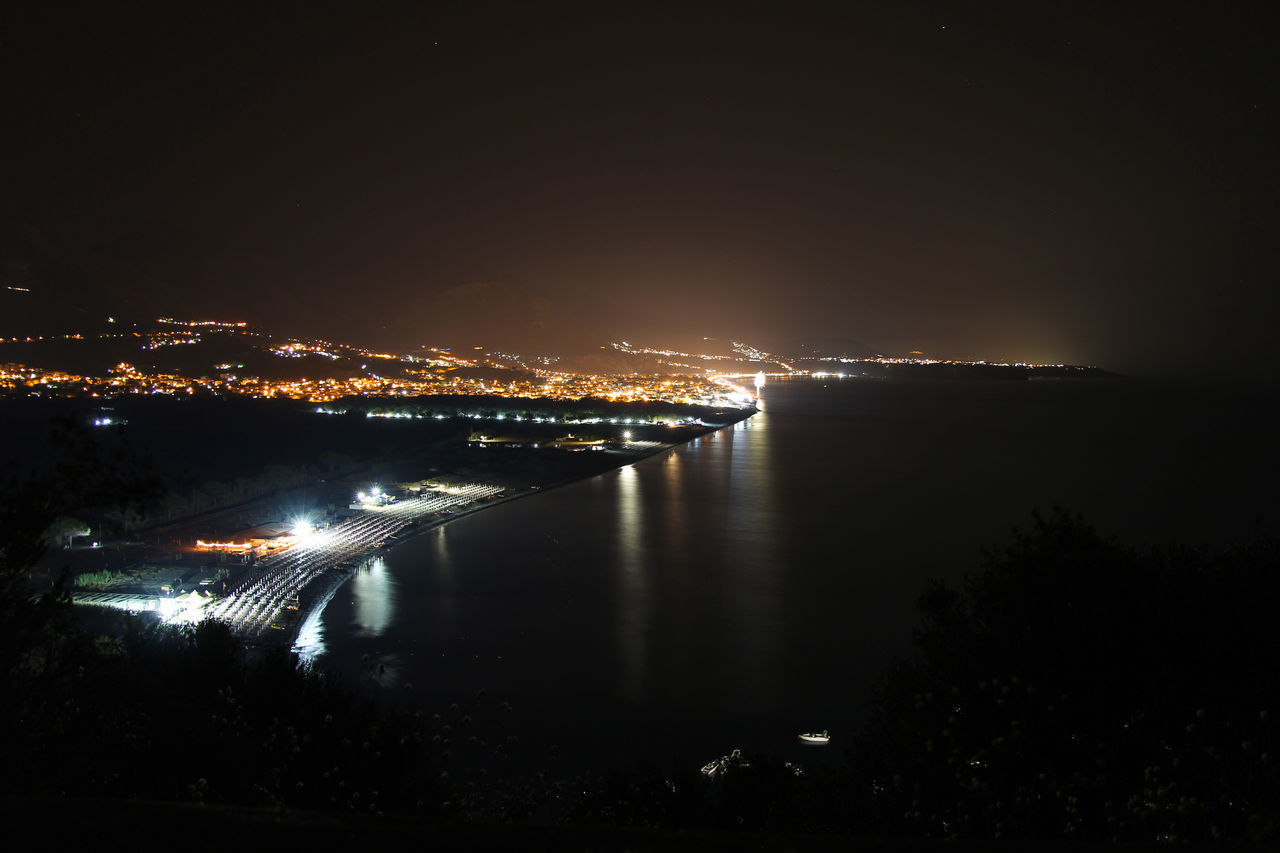 ILLUMINATED CITY BY SEA AT NIGHT