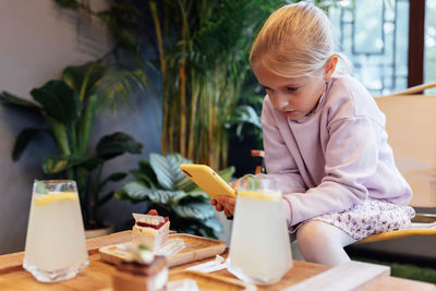 Side view of woman sitting on table at home