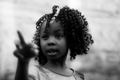 Close-up of girl with frizzy curly hair pointing outdoors