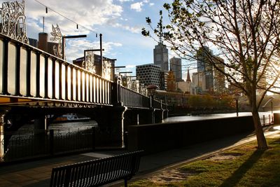 Bridge over river by buildings in city against sky