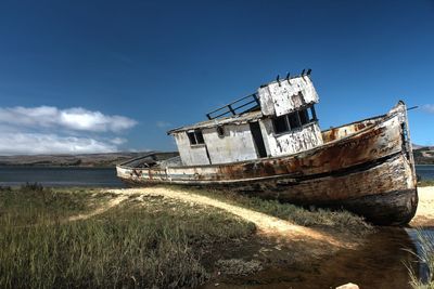 Abandoned boat at shore against sky