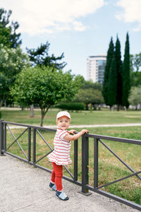 Cute boy standing by trees against plants