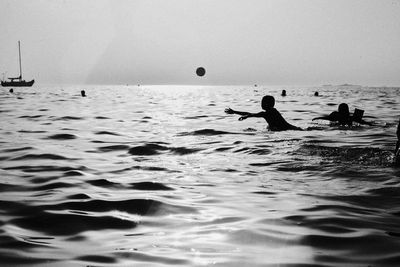 Silhouette people enjoying in sea against sky