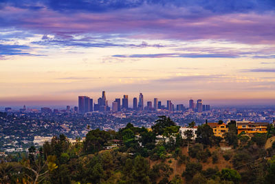 Modern buildings in city against sky during sunset