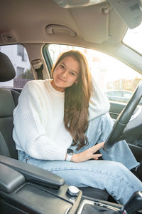 Portrait of young woman sitting in car