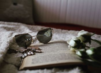 Close-up of sunglasses with book and decoration on table
