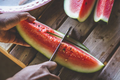 Close-up of man cutting watermelon slices on table