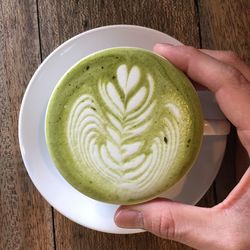 Close-up of woman holding coffee cup on table