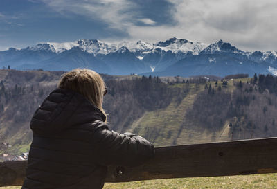 Rear view of woman looking at mountains against sky