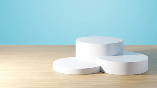 Close-up of white candles on table against blue wall