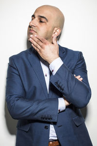 Mid adult serious businessman looking way while standing against wall