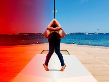 Rear view of woman standing on beach against sky