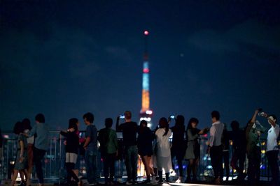 People standing in illuminated city at night