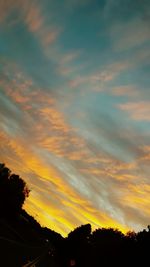 Silhouette trees against dramatic sky during sunset