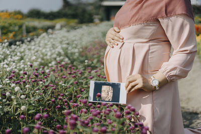 Midsection of woman holding umbrella standing on field