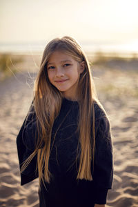 Portrait of a girl with long hair run on a sandy beach in a black leather jacket