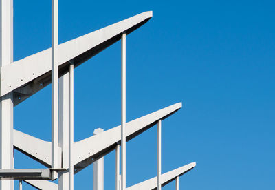 Low angle view of telephone pole against clear blue sky