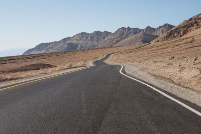 Scenic view of road by mountains against sky