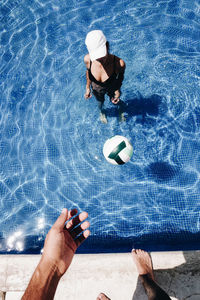 Low section of man with ball in swimming pool