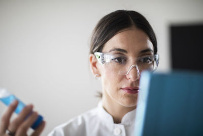 Scientist female with lab glasses, tablet and tubes in a lab