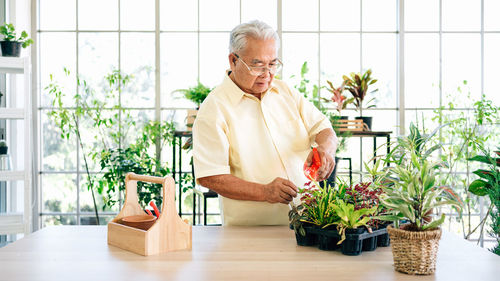 Midsection of man holding potted plant on table