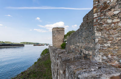 Stone wall by sea against sky