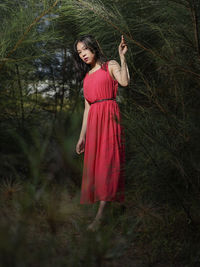 Young woman standing on field against trees