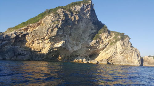 Scenic view of sea and mountains against clear blue sky