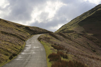 Road leading towards mountain against sky