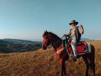 Horse riding motorcycle on field against sky