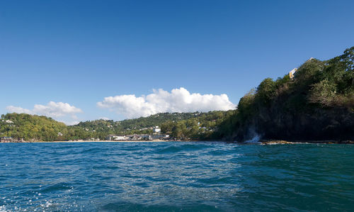 Scenic view of blue sea and mountains against sky