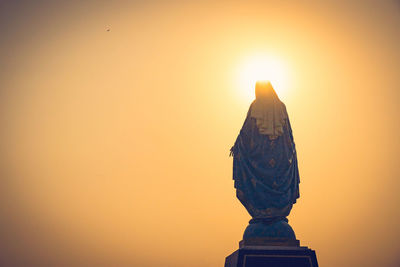 Statue of temple against orange sky