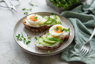 Bread toast, boiled eggs, avocado slice, microgreens on a plate, breakfast time