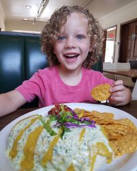 Portrait of smiling girl having food on table at home