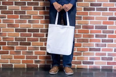 Low section of man standing against brick wall