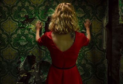 Rear view of woman wearing red dress while standing in abandoned house
