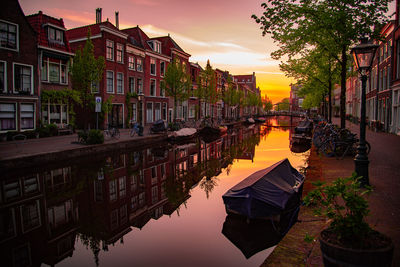 Canal amidst buildings against sky during sunset