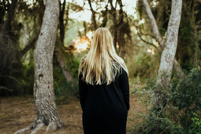 Rear view of woman standing in forest