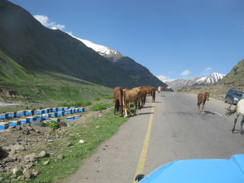 Road leading towards mountains against clear sky