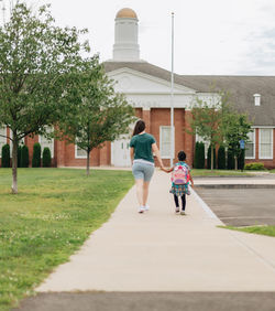 Young millennial mother sending daughter off back to school