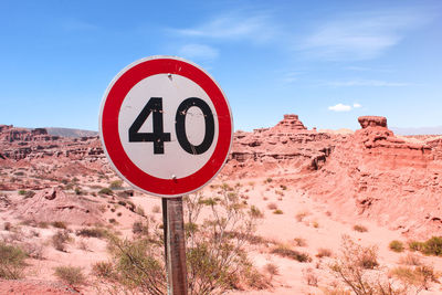 Road sign on landscape against sky