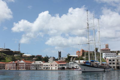 Sailboats moored on harbor by sea against sky