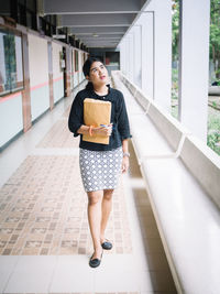 Portrait of young woman standing against building