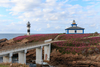 Lighthouse by building against sky